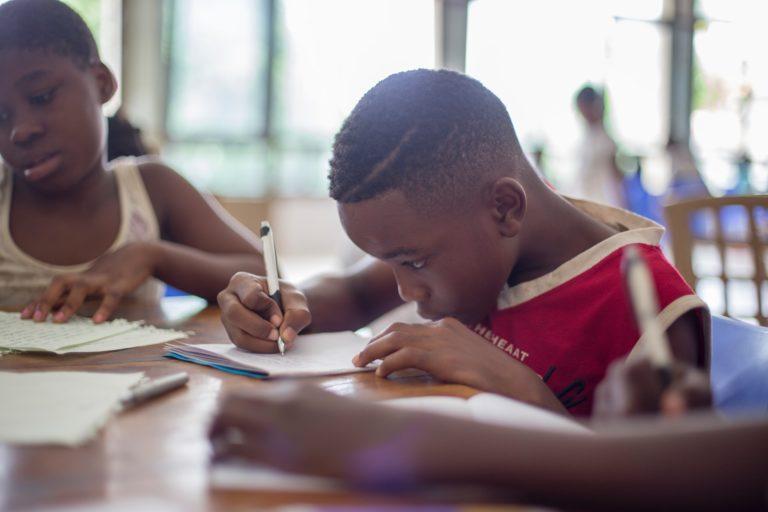 two children sat at a desk drawing