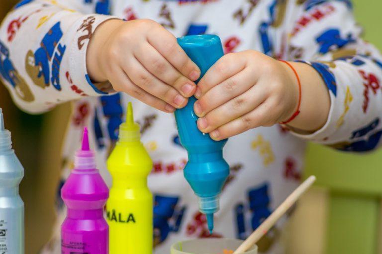 kid squeezing blue paint bottle