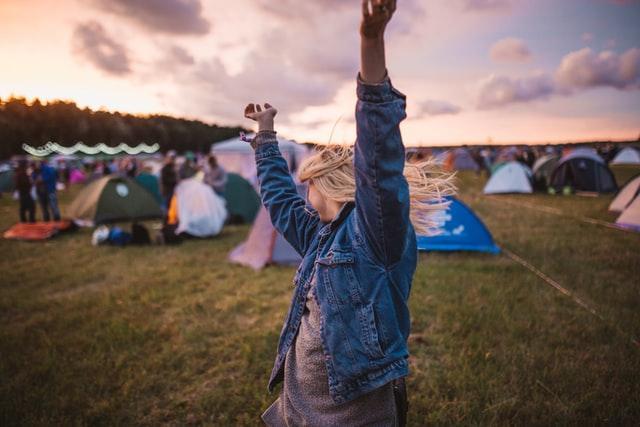 a photo of a woman in a field with her arms in the air. She is dancing