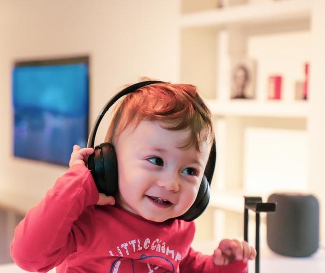 small, very happy kid listening to a podcast through big headphones