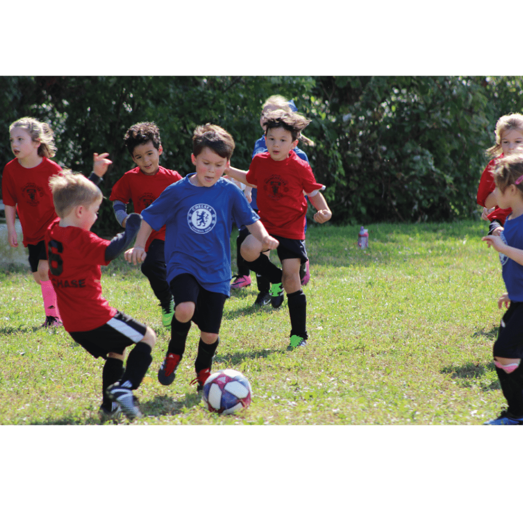 Kids playing football on a field in red and blue kits