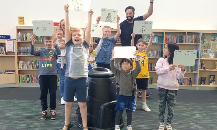 Children holding up whiteboards with their recycling pledges on.