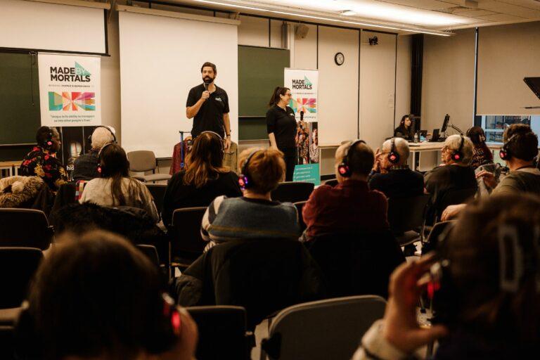 Two presenters speak into microphones at the For Data's Sake event, with the audience listening through silent disco headphones.