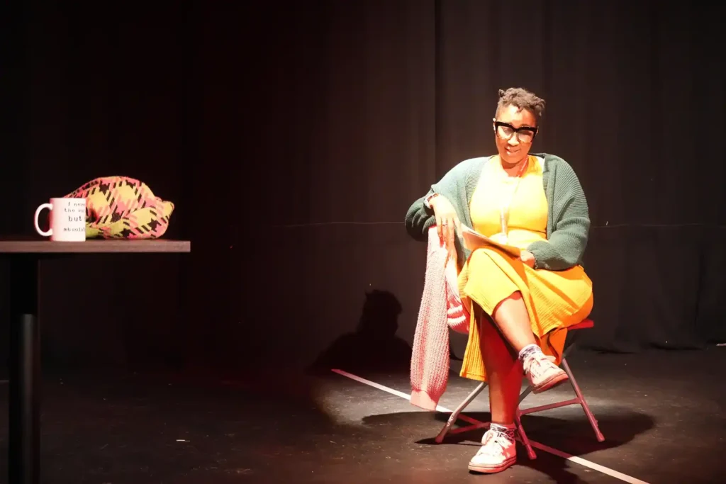 Woman on stage narrating a shared experience through engaging theatre