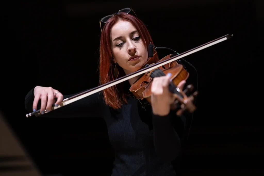 Woman playing violin in theatre production